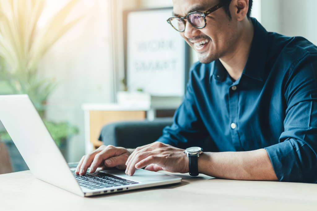 man-with-blue-button-up-smiling-at-laptop